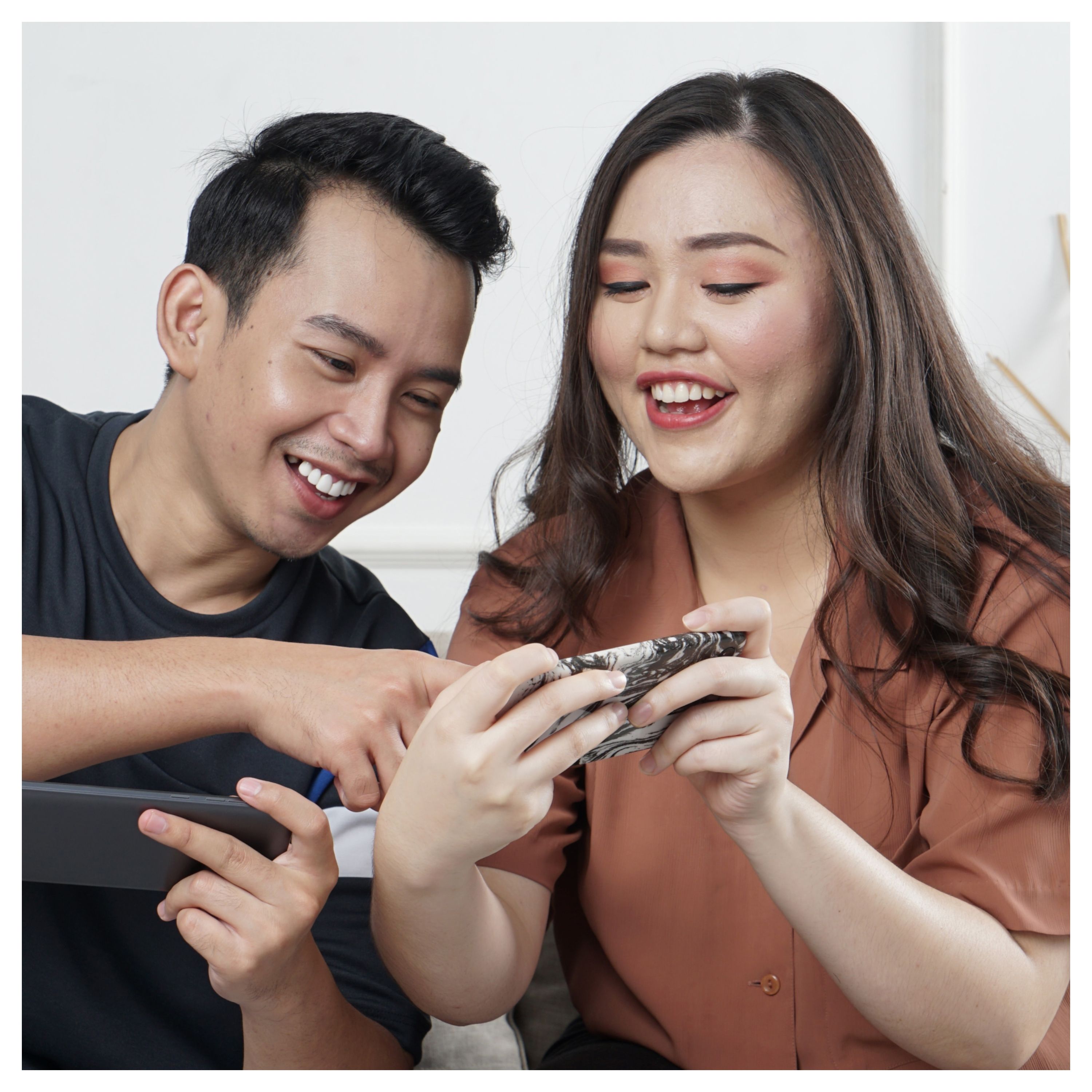 Un couple regardent un écran de téléphone portable en souriant