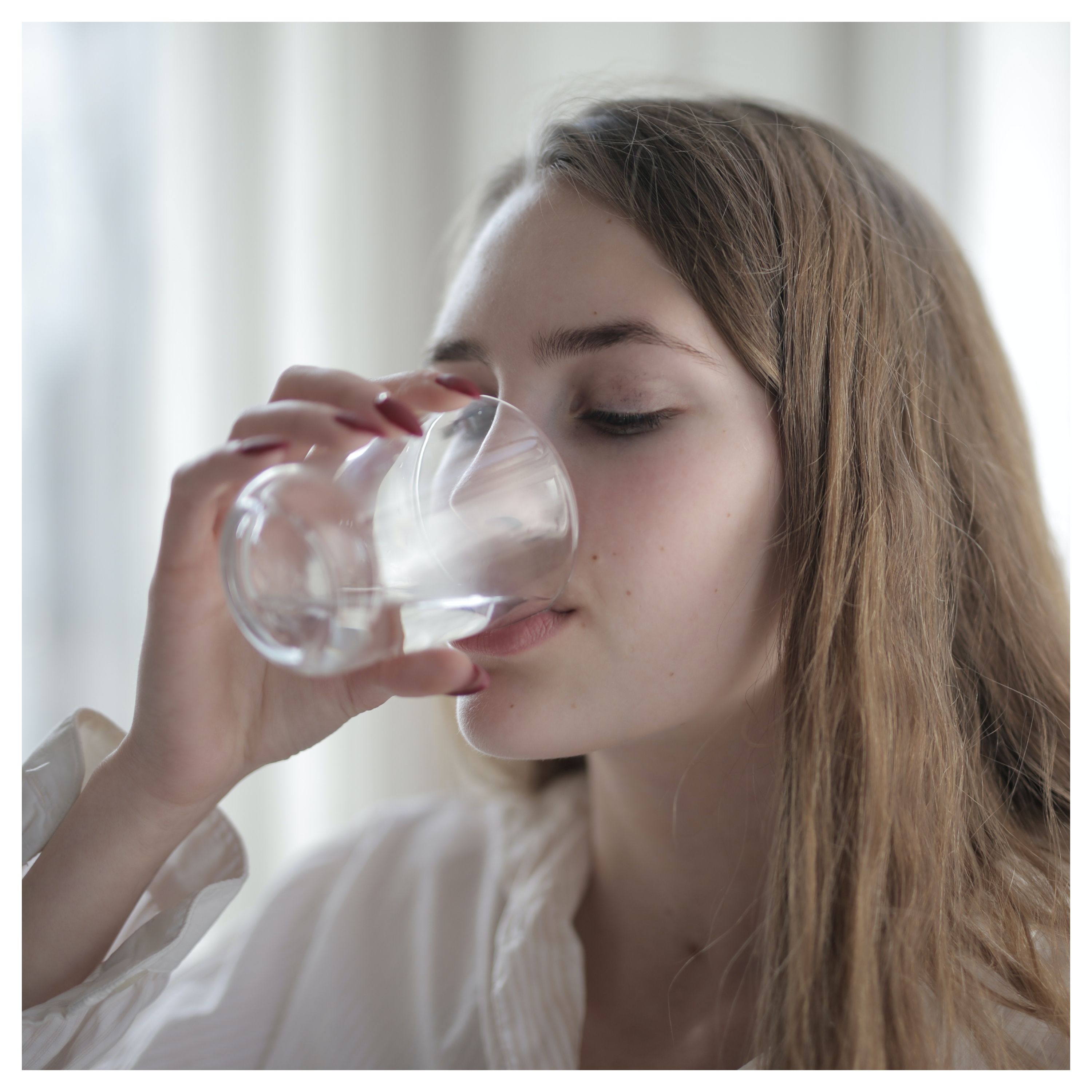 Une jeune femme boit de l'eau dans un verre