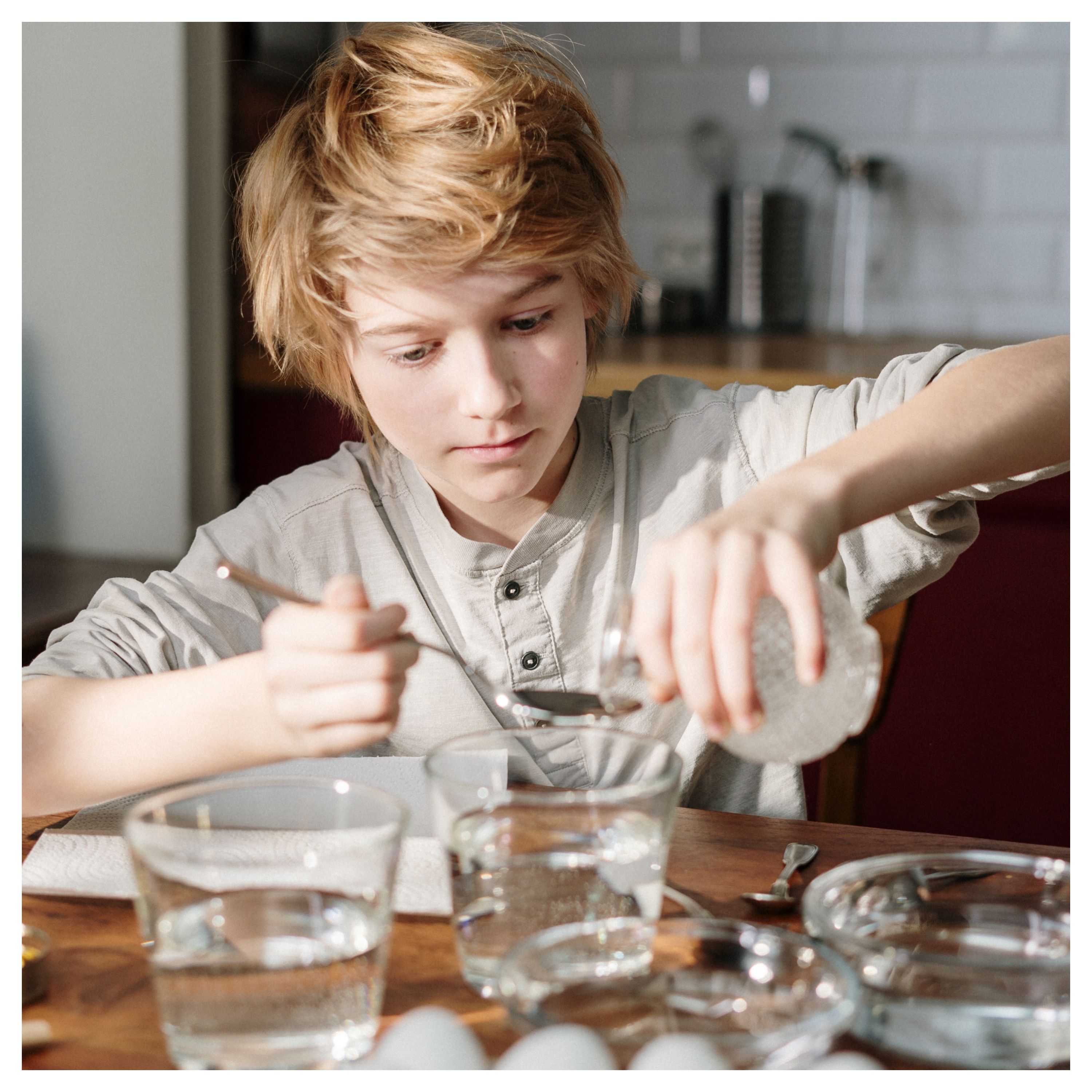 Un jeune garçon verse du vinaigre blanc dans une cuillière à soupe