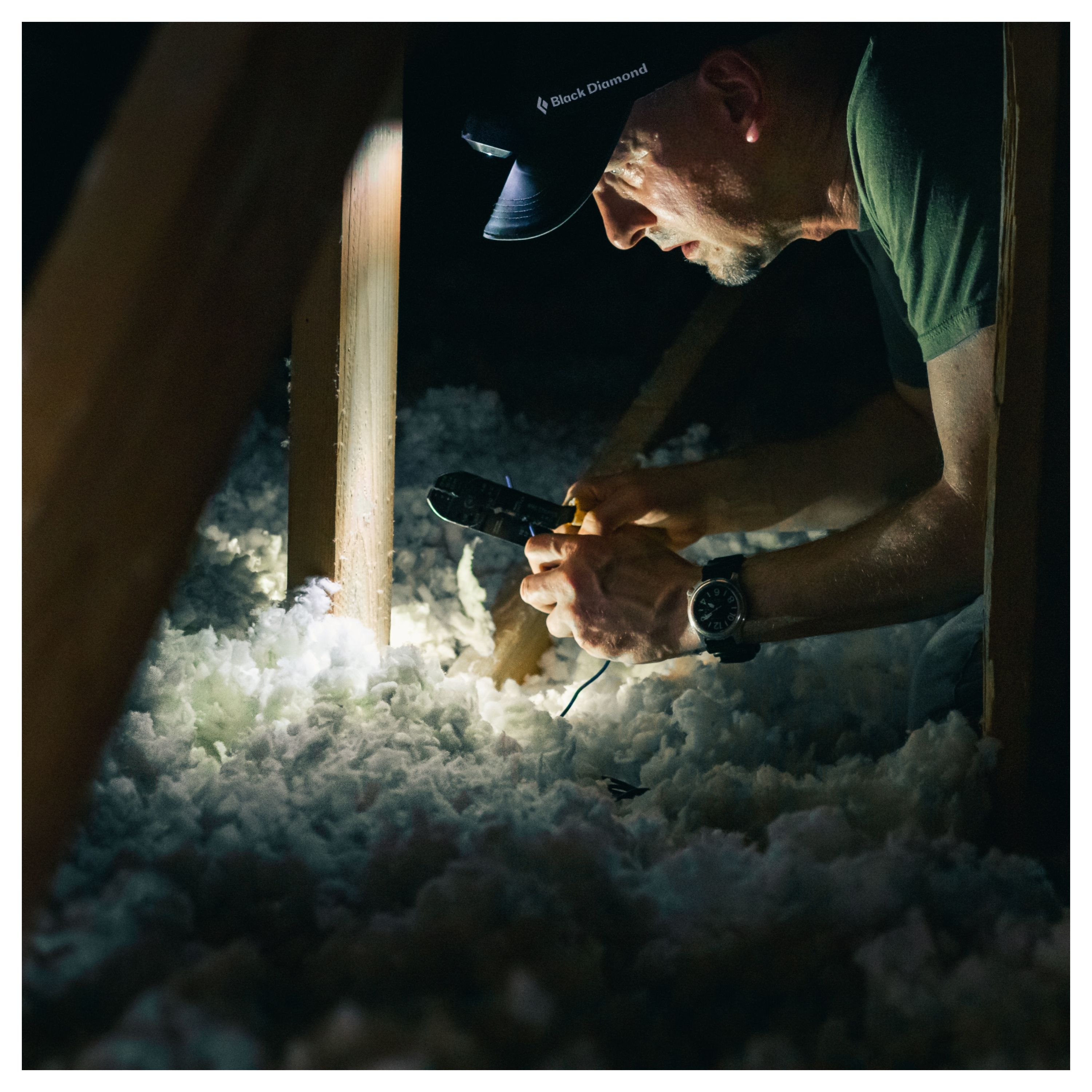 Un homme met de la laine de verre sous un toit pour mieux l'isoler