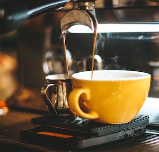 Du café coule dans une tasse jaune depuis une machine à café