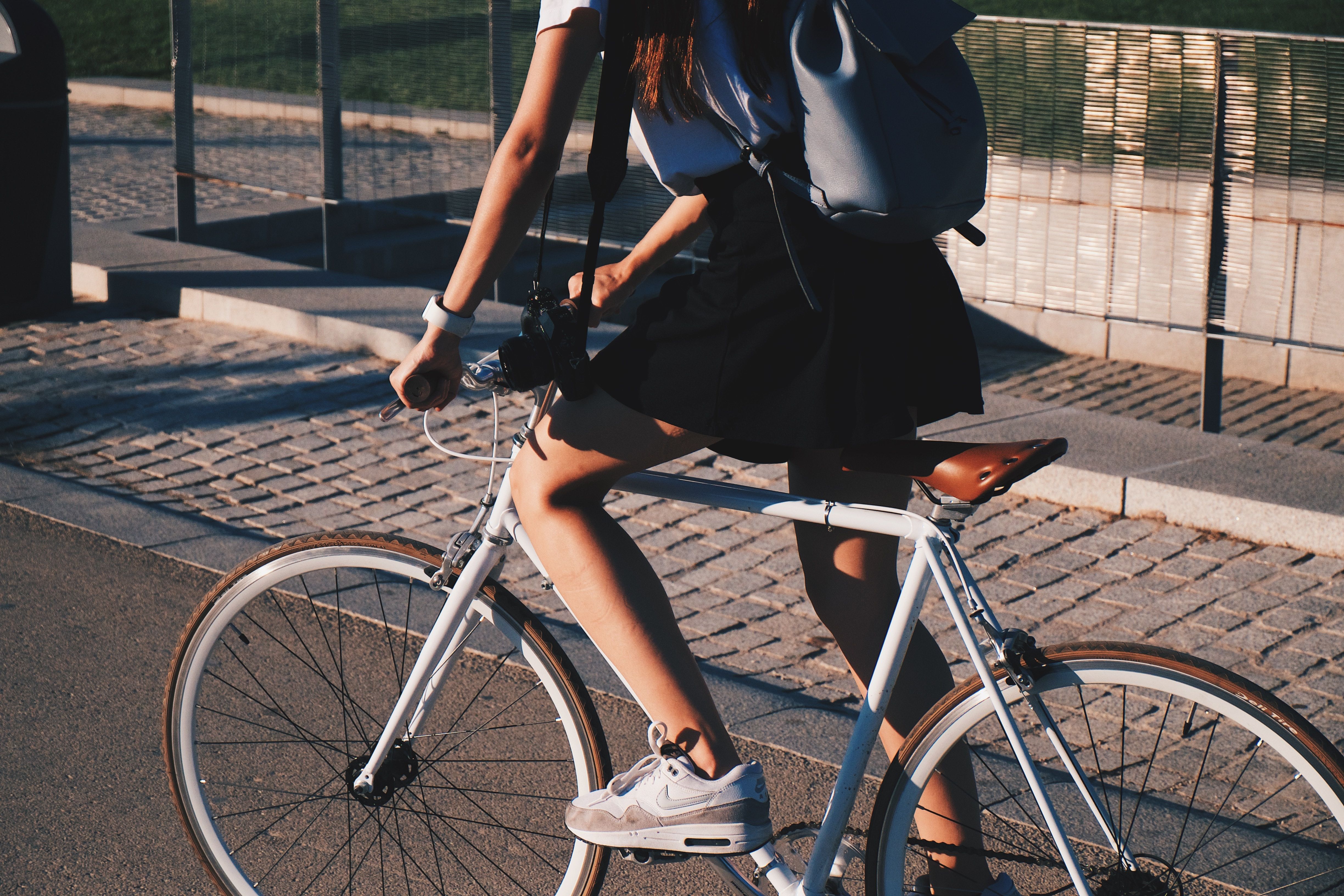 Une femme en jupe noire avec un sac à dos pédale sur son vélo