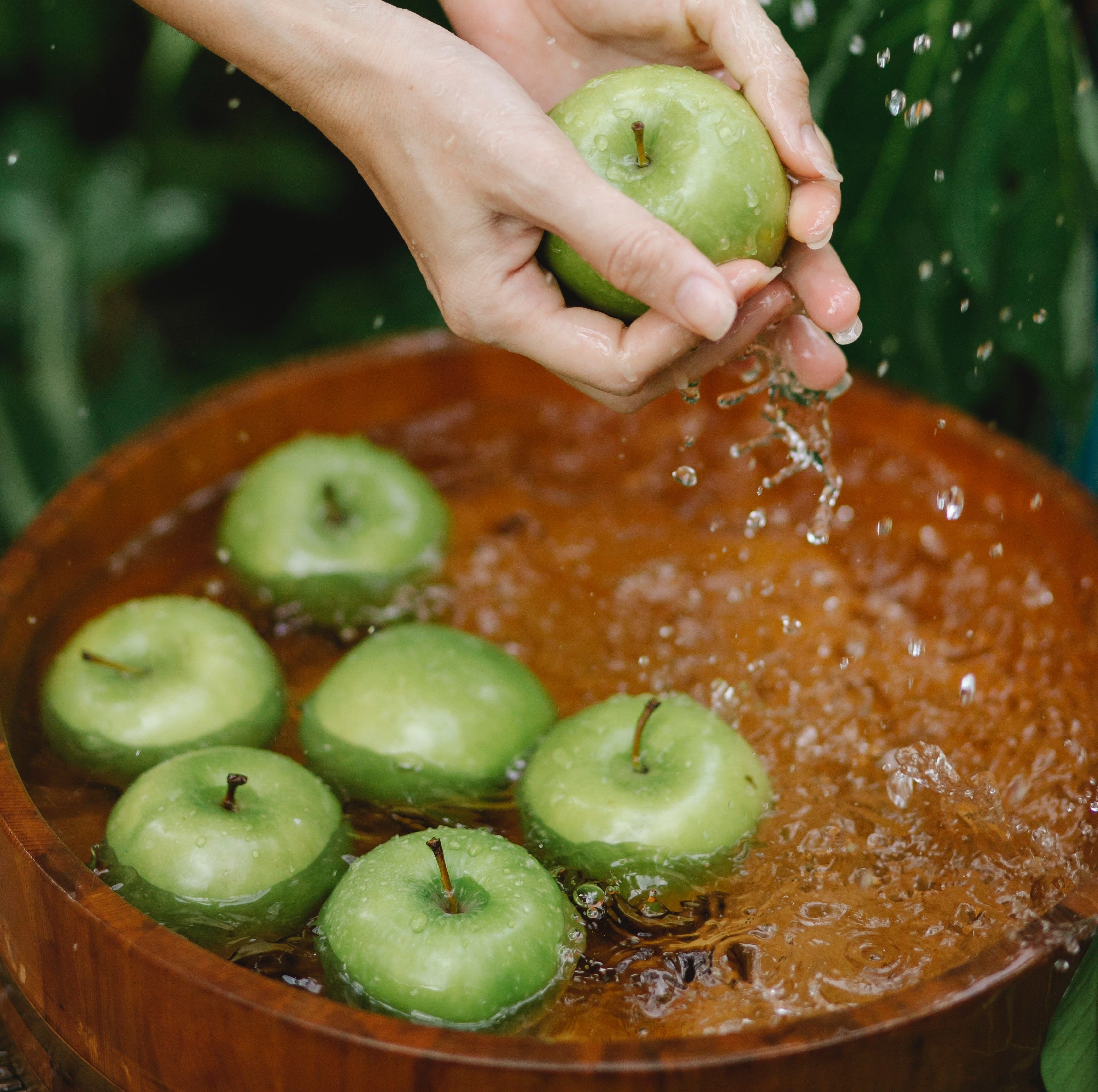 Une personne rince des pommes vertes avec de l'eau