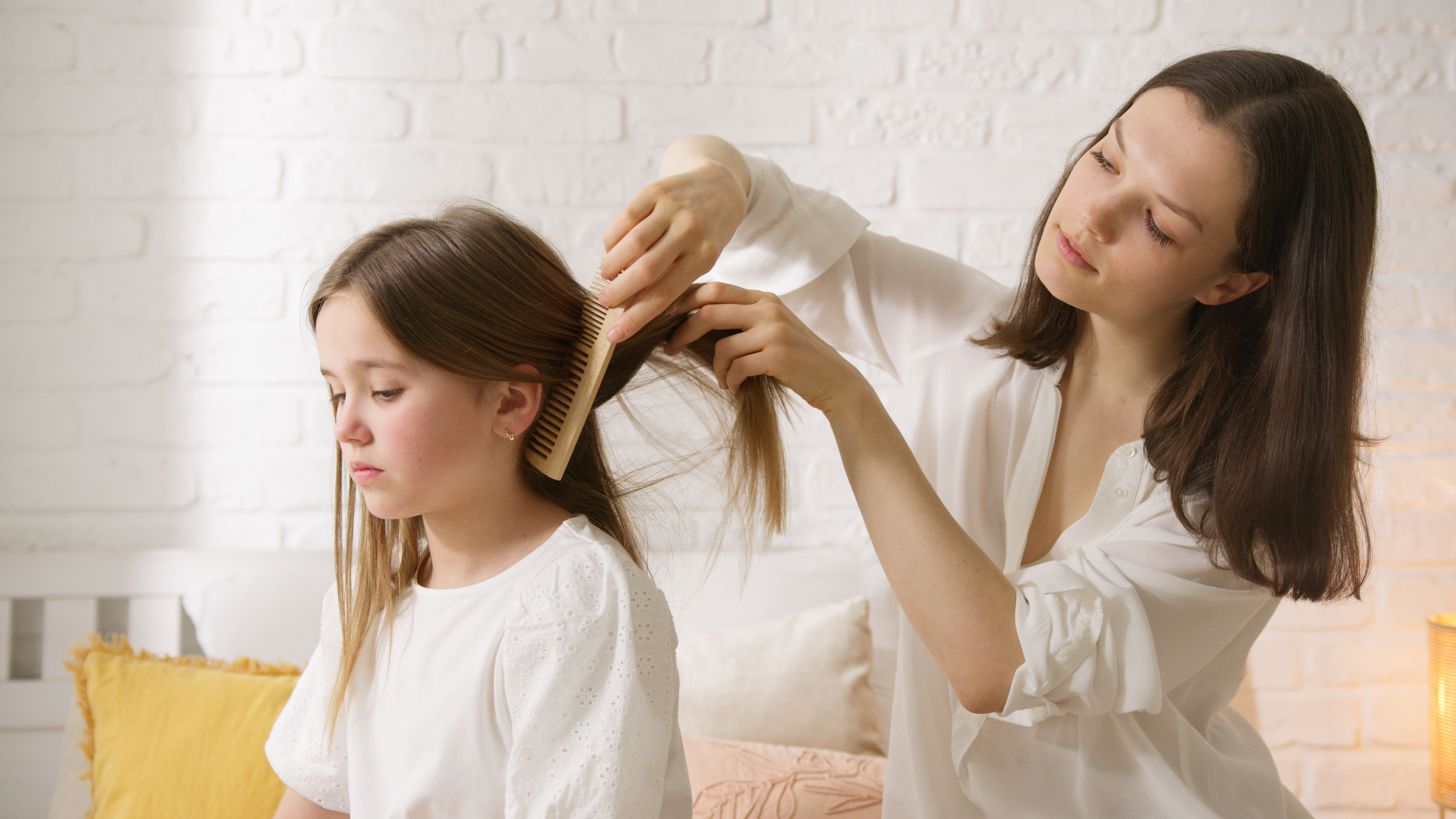 Une femme brosse les cheveux d'une petite fille avec un peigne