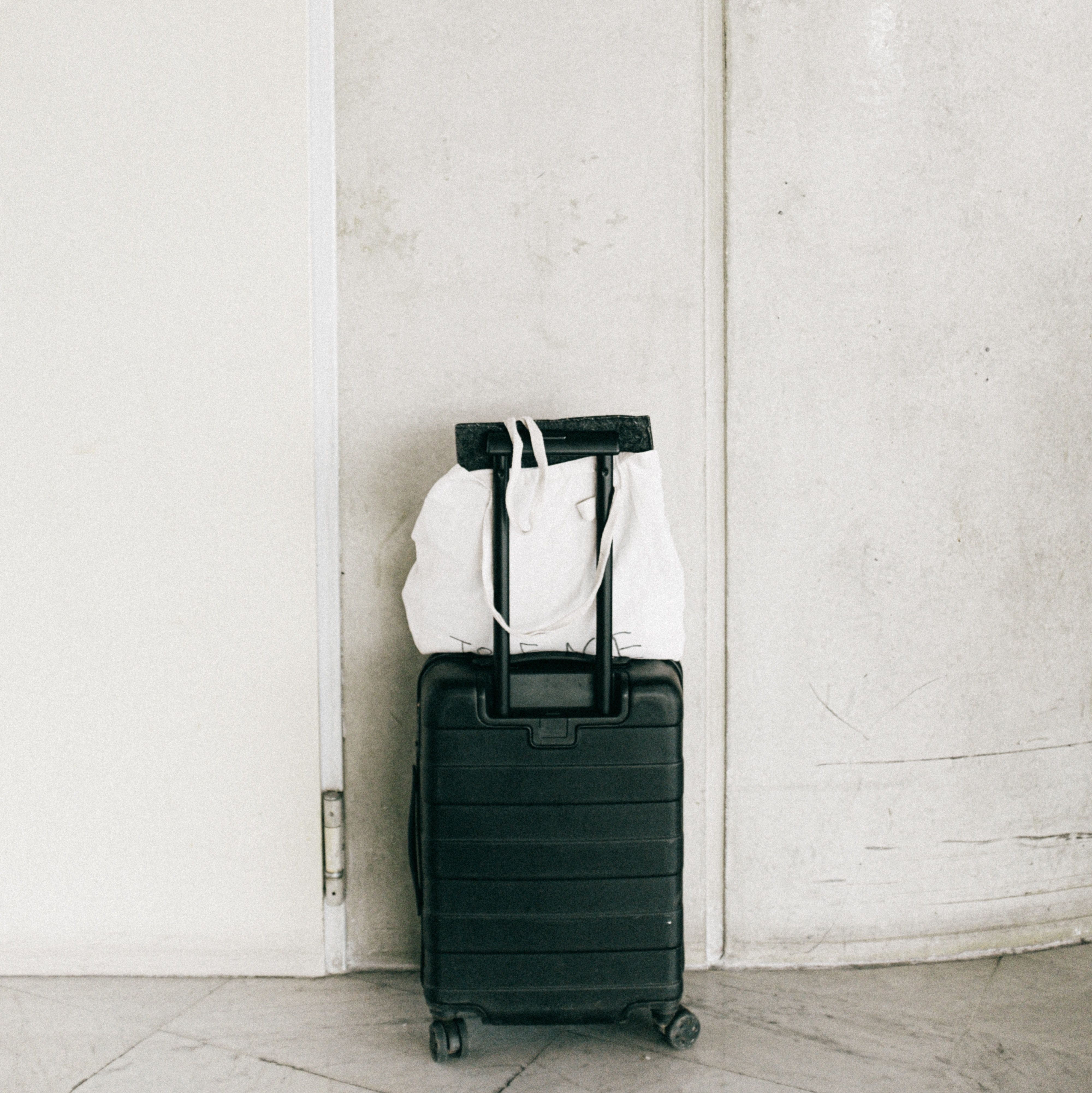 une valise noire à côté d’un mur blanc