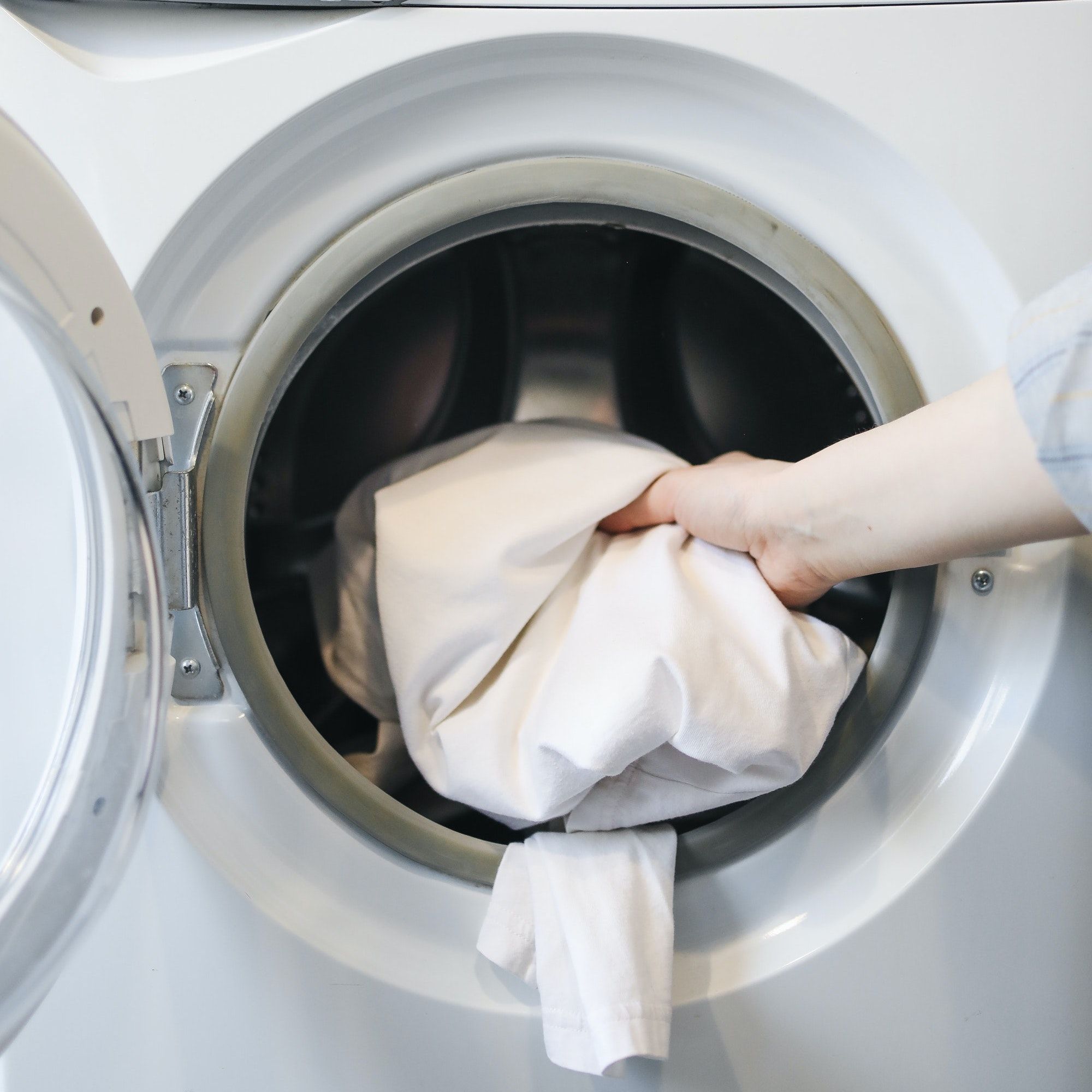 une personne tenant une serviette blanche dans une machine à laver blanche