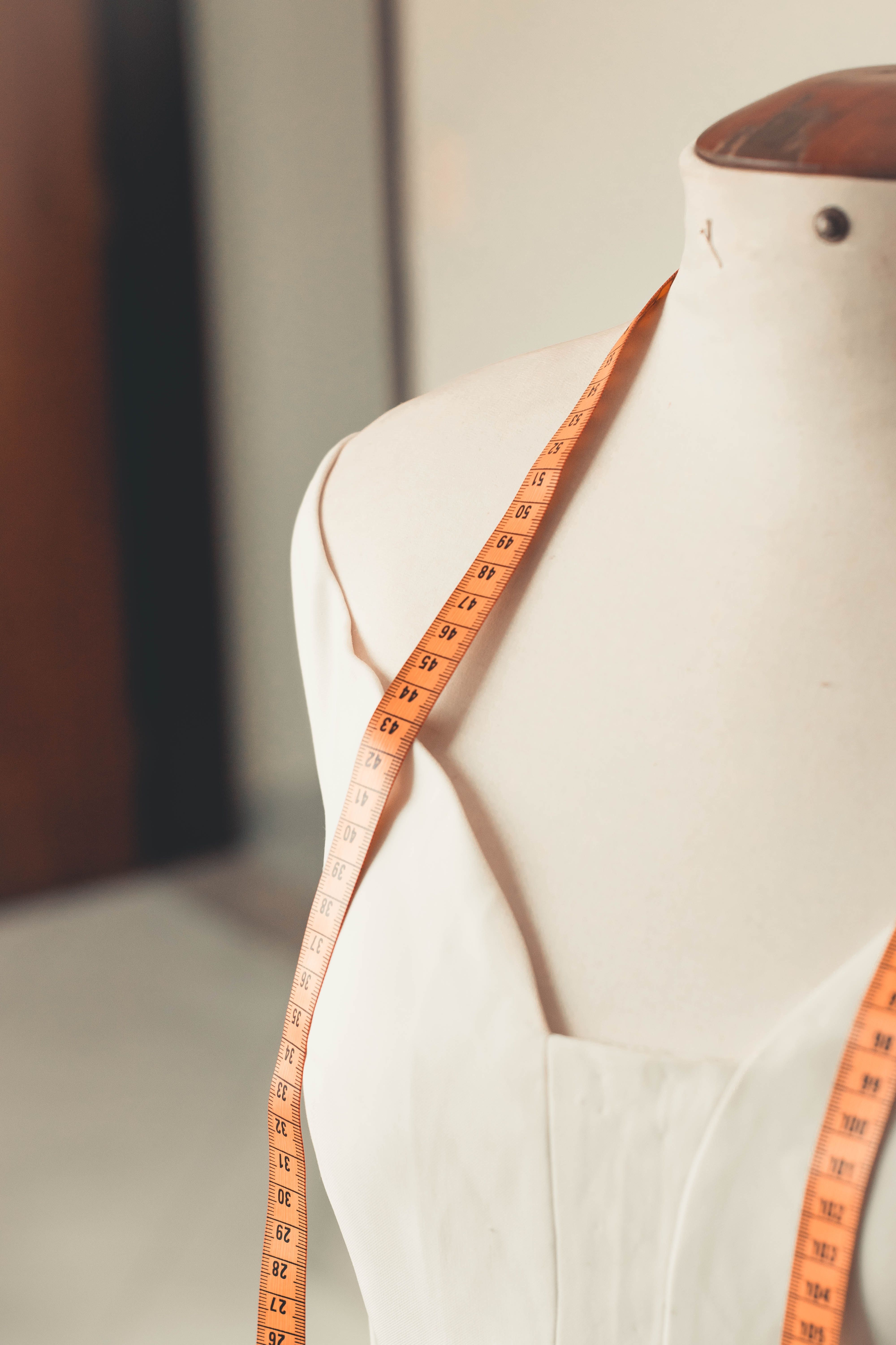 Un ruban mesureur est disposé sur un mannequin sans tête avec une robe blanche