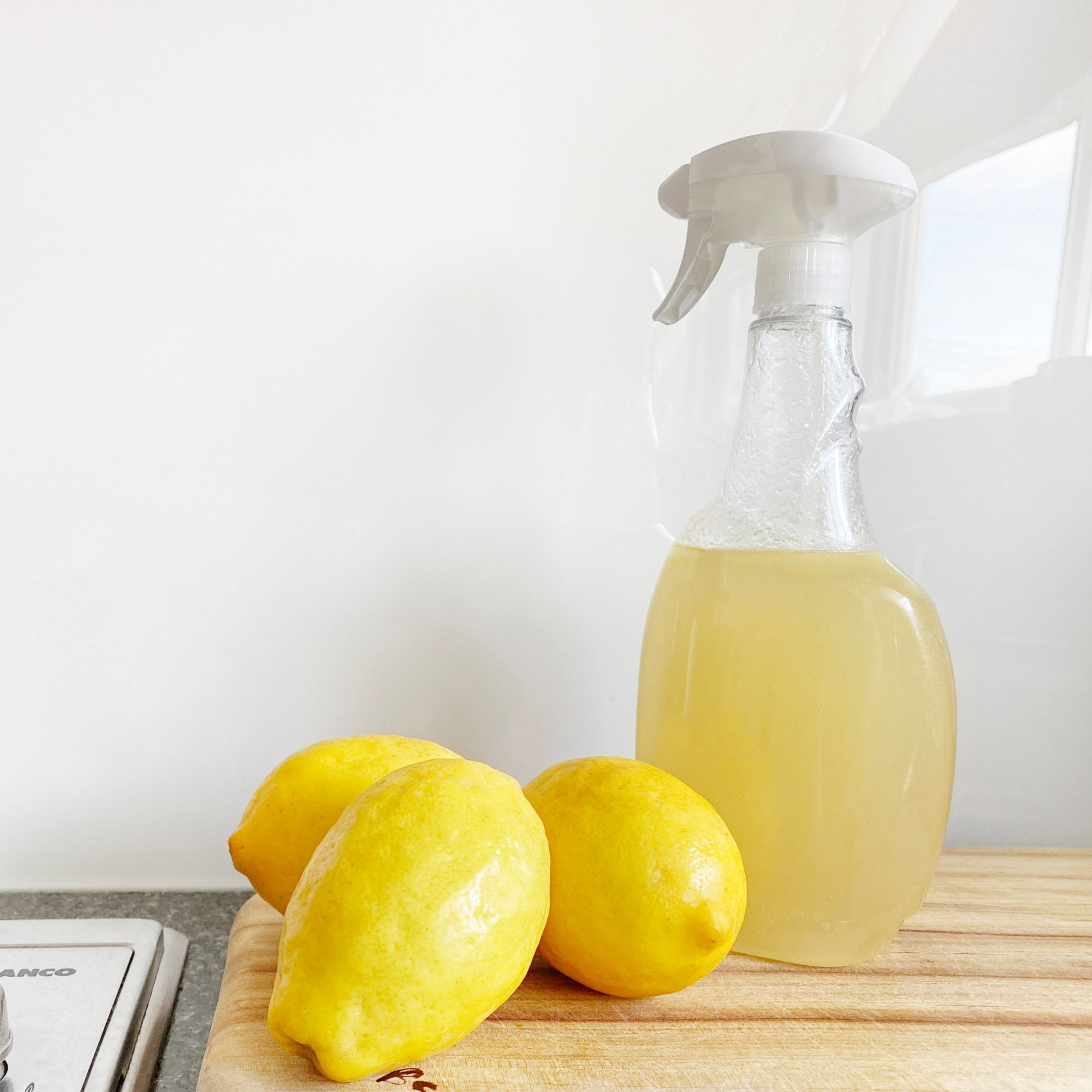 Trois citrons jaunes à côté d'un pulvérisateur contenant du vinaigre